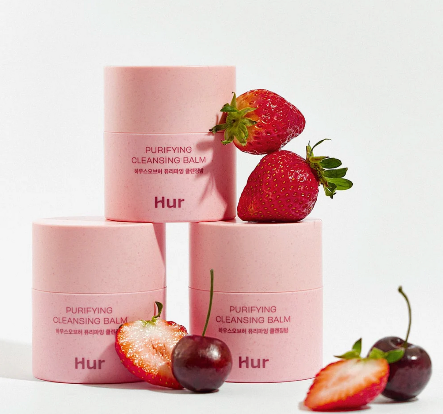 Pink skincare products with strawberries and cherries on a white background