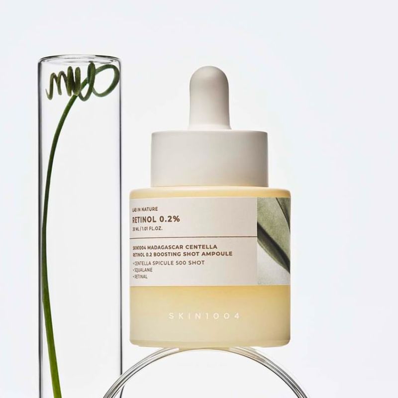 Skincare ampoule bottle with dropper and clear packaging on a light gray background