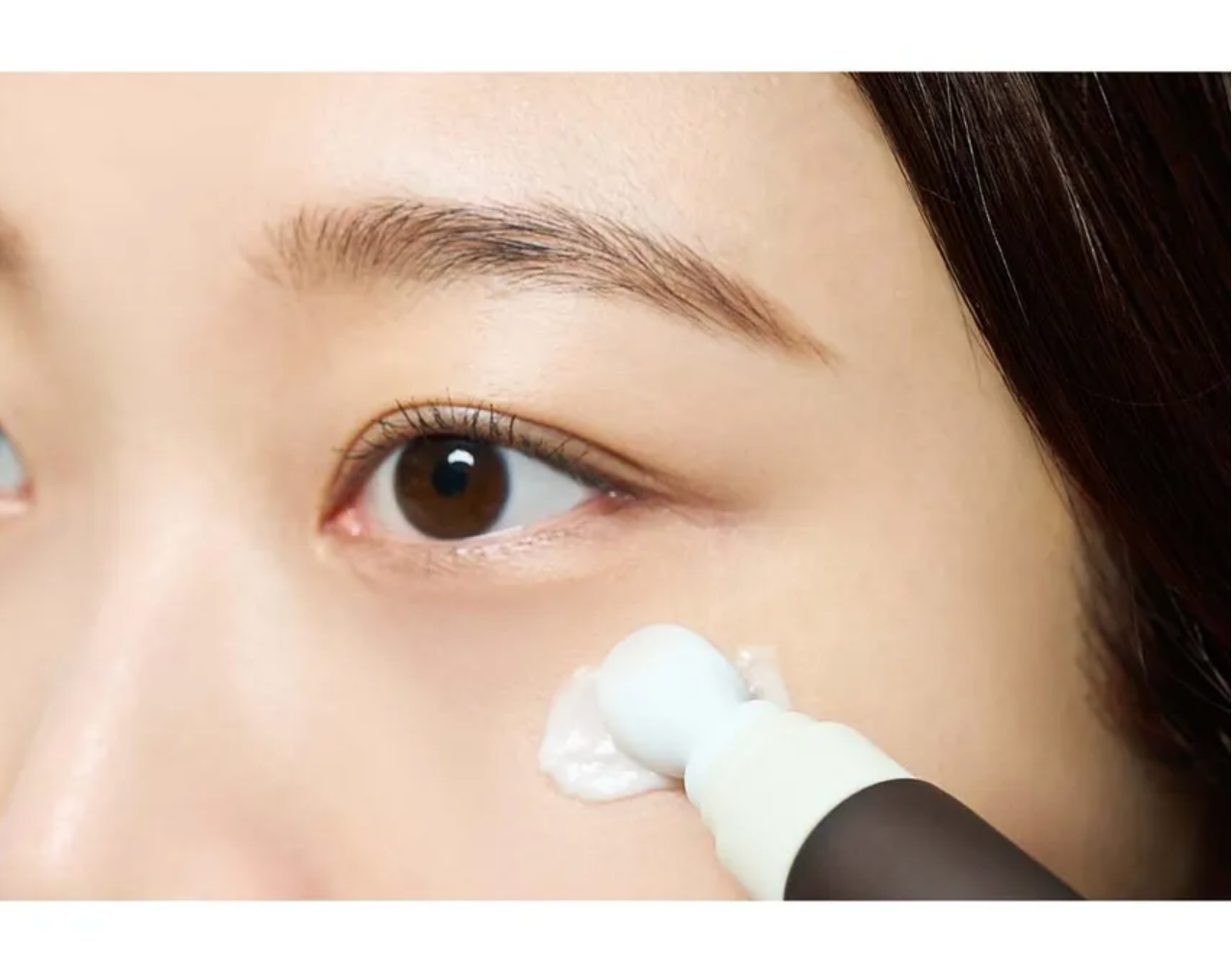 Close-up of a person applying cream to their face with a brush.