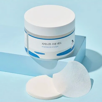 Cosmetic jar with two pads on a light blue background