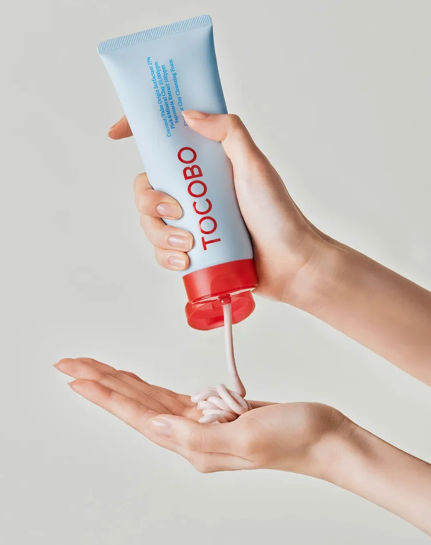 Hand holding a tube of Tocobo cream with a light gray background