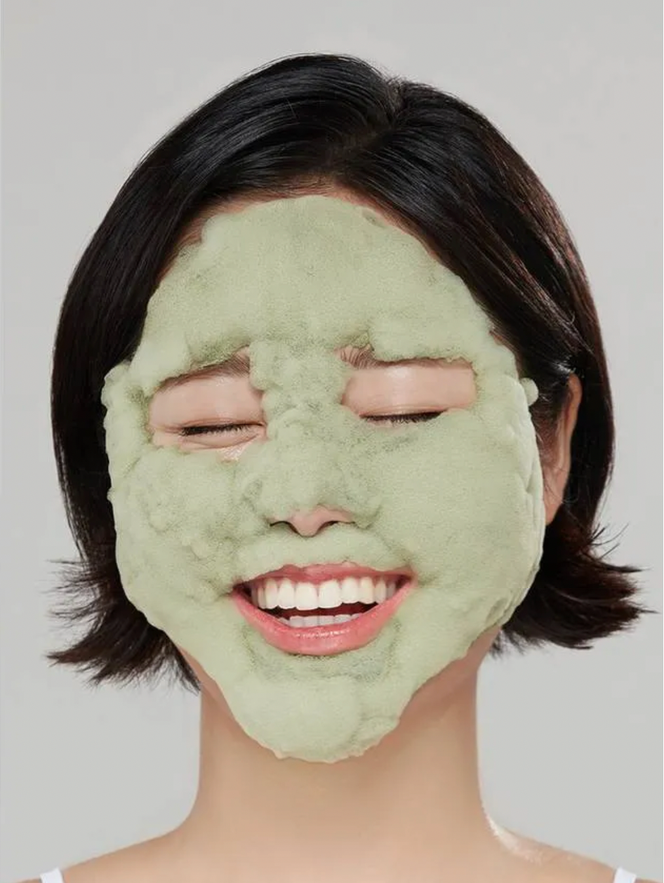 Person wearing a green face mask against a plain background