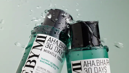 Two skincare bottles labeled 'AHA.BHA.PHA 30 Days' with water droplets on a light gray background.