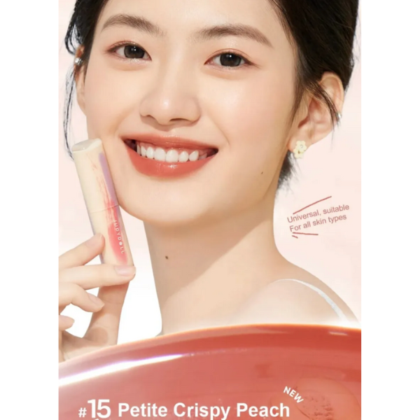Woman holding a cosmetic product with 'Petite Crispy Peach' color swatch on a light pink background